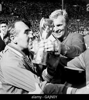 England gegen Westdeutschland - Weltcup-Finale 1966 - Wembley-Stadion. Der jubelende englische Kapitän Bobby Moore (r) zeigt nach dem Sieg über 4-2 die Jules Rimet-Trophäe an Manager Alf Ramsey (l). Stockfoto