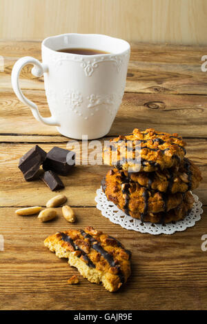 Chocolate Cookies mit Erdnüssen und Tee auf einem rustikalen Holztisch, vertikale Vereisung. Frühstück Gebäck und Tee. Stockfoto