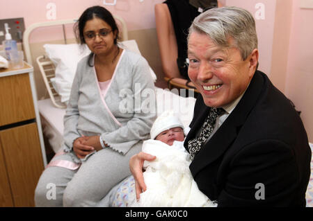 Gesundheitsminister Alan Johnson hält das heute Morgen früh geborene Baby-Binyamin, während Mutter Zahida Aslam im Royal Victoria Infirmary aufschaut. Stockfoto