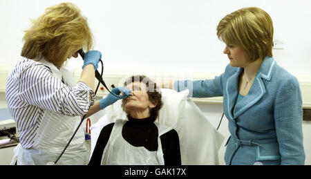 Die schottische Gesundheitsministerin Nicola Sturgeon (rechts) beobachtet, wie Gillian MacDougall, Leiterin der Hals-Direktion, während eines Besuchs im St. John's Hospital in Livingston, Schottland, eine Nasenendoskopie an der Patientin Alisa Evans durchführt. Stockfoto