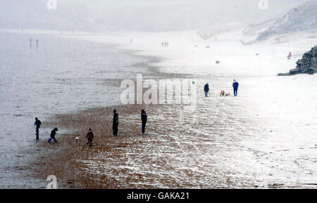 An einem kalten Ostersonntag fahren die Menschen an einen schneebedeckten Tynemouth Beach, Tyne, und tragen diesen im Nordosten Englands. Stockfoto