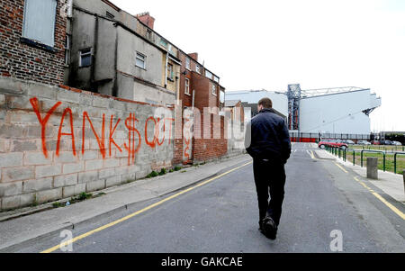 Ein Mann geht an Graffitti in der Nähe des Stadions des Fußballvereins Liverpool vorbei und zeigt die Unruhe der Fans über den amerikanischen Besitz des Clubs. Stockfoto