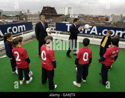 Sir Trevor Brooking und der englische Manager Fabio Capello des Verbands mit Kindern der St. John's School in Fulham auf dem Dach des FA-Hauptquartiers in Soho Square, London, um eine Investition von 200 Millionen in den Breitenfußball anzukündigen. Stockfoto