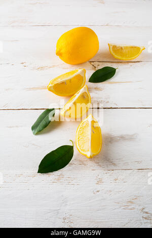 Saftige Zitronen mit Blättern auf einem weißen Hintergrund aus Holz, vertikale. Zitronenscheiben. Zitrone. Zitronen. Zitrus. Obst. Früchte. Frische Zitrone Stockfoto