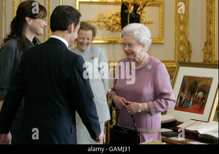 Der französische Präsident Nicolas Sarkozy und seine Frau Carla Bruni-Sarkozy sprechen mit der britischen Königin Elizabeth II., da sie Gegenstände aus der Königlichen Sammlung im Schloss Windsor zeigen. Stockfoto