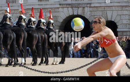 Volleyball üben auf der Horse Guards Parade. Beachvolleyball die olympische Hoffnung, Denise Johns, praktiziert, während die Kavallerie im Haushalt die Wache auf der Horse Guards Parade wechselt. Stockfoto