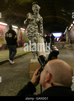 Ein Fotograf inspiziert eine Statue des Graffiti-Künstlers Banksy (genannt 'Brew-Periode') beim 'Cans Festival' in einem Straßentunnel in Leake Street, Lambeth, London. Stockfoto