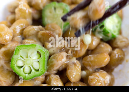 Nahaufnahme von Okra und fermentierten Sojabohnen bekannt als Natto in Japan mit Essstäbchen. Japanische traditionelle Speisen aus Sojabohnen. Stockfoto