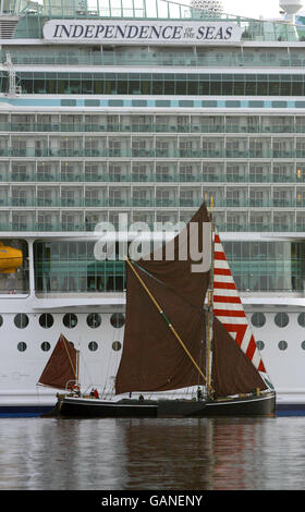 Thames Barge Alice segelt am größten Kreuzfahrtschiff der Welt, der Independence of the Seas, vorbei, als sie heute zum ersten Mal in Southampton in Großbritannien ankommt. Das riesige 160,000-Tonnen-Schiff wird den Rest des Jahres von der Stadt aus operieren. Das von Royal Caribbean International gebaute 400-Millionen-Schiff ist zusammen mit ihren Schwesterschiffen Freedom of the Seas und Liberty of the Seas das größte Kreuzfahrtschiff der Welt. Stockfoto