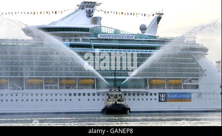 Ein Feuerwehrschlepper begrüßt das größte Kreuzschiff der Welt, die Independence of the Seas, als sie heute zum ersten Mal in Southampton in Großbritannien ankommt. Das riesige 160,000-Tonnen-Schiff wird den Rest des Jahres von der Stadt aus operieren. Das 400 Millionen Schiff, das von Royal Caribbean International gebaut wurde, ist zusammen mit ihren Schwesterschiffen Freedom of the Seas und Liberty of the Seas das größte Kreuzschiff der Welt. Stockfoto