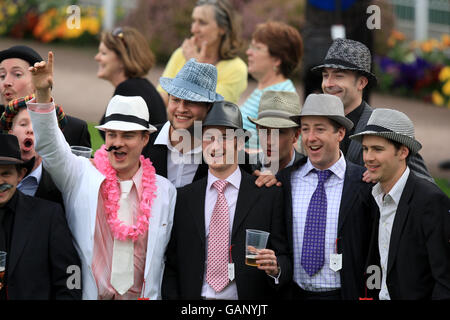 Racegoers genießen einen Drink, während die Saw Doctors während eines Konzerts am Ende des Gold Cup Meetings im Sandown Park auftreten. Stockfoto