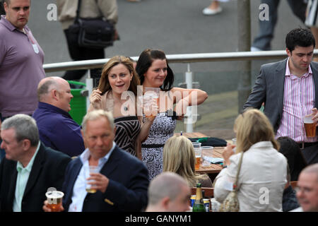 Pferderennen - Bet365 Gold Cup Meeting - Sandown Park. Racegoers genießen einen Drink, während die Saw Doctors während eines Konzerts am Ende des Gold Cup Meetings im Sandown Park auftreten. Stockfoto