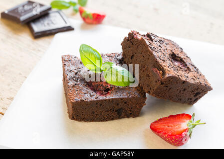 Nahaufnahme von Schokoladen-Brownie Kuchen mit Erdbeeren garniert und arrangiert auf weißen Teller. Selektiven Fokus Stockfoto