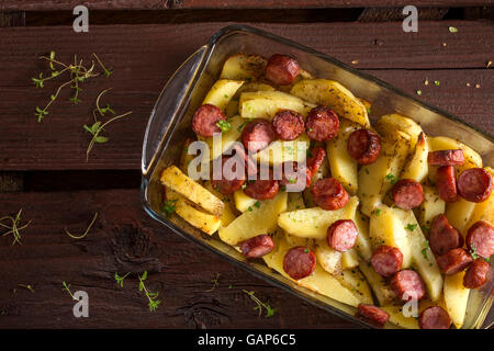 Tablett mit Bratkartoffeln mit Würstchen und Gewürzen auf hölzernen Hintergrund Stockfoto