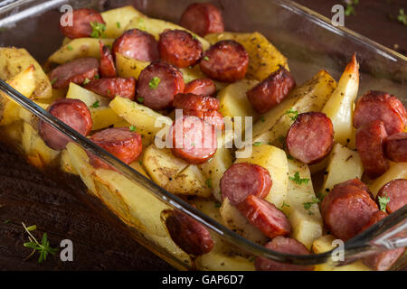 Tablett mit Bratkartoffeln mit Würstchen und Gewürzen auf hölzernen Hintergrund Stockfoto