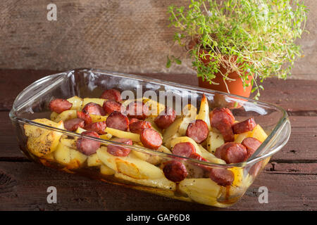 Tablett mit Bratkartoffeln mit Würstchen und Gewürzen auf hölzernen Hintergrund Stockfoto