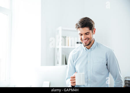 Fröhliche junge Geschäftsmann lächelnd und Kaffeetrinken im Büro Stockfoto