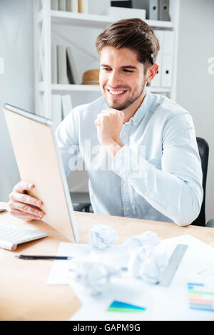 Glückliche junge Geschäftsmann Notenlesen in Notpad am Arbeitsplatz Stockfoto