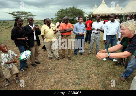 Sir Richard Branson wirft einen Ball mit einem einheimischen Kind, nachdem er die Patenschaft der Kenya Rugby 7 Mannschaft in Nairobi in Kenia durch Virgin Atlantic verkündet hat. Stockfoto