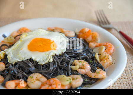 Schwarze Spaghetti mit Spiegelei, Krabben, Knoblauch und Petersilie. Stockfoto