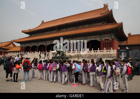 Chinesische Studenten auf einem Ausflug mit ihren Lehrern in der verbotenen Stadt, warten sie ruhig vor dem Tor der höchsten Harmonie. Stockfoto