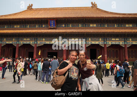 Frau nutzt eine Smartphone ein Selbstporträt von ihr und ihrem Mann vor der Halle der höchsten Harmonie, viele Touristen herum. Stockfoto