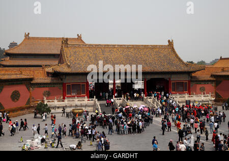 Touristen besuchen das Tor der Himmlischen Reinheit in der verbotenen Stadt, dazwischen Arbeiter die Boden-Fliesen reparieren. Peking, China. Stockfoto