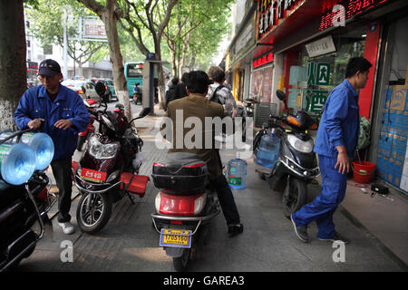 Ein chinesischer Mann reitet auf seinem Roller in der Regel auf dem Bürgersteig, er ist sehr schnell zwischen anderen Rollern und Fußgänger manövrieren. Suzhou, China. Stockfoto