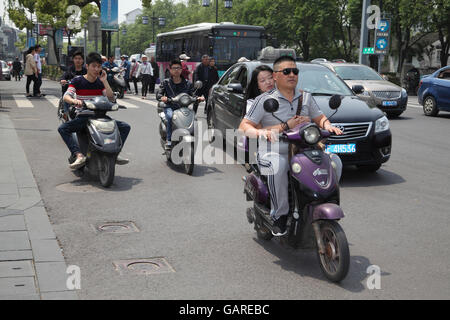 Einer chinesischen Verkehr Szene, Motorräder fahren Autos, ein Fahrer nutzt sein Handy während der Fahrt und Menschen Fuß zwischen den Fahrzeugen. Stockfoto