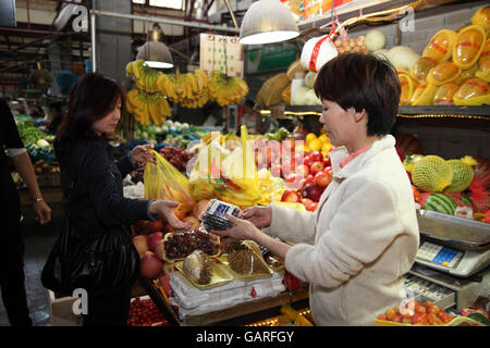 Einen bunten Obst und Gemüse Markt im Bereich Tianzifang, hier eine Frau kauft eine Schachtel mit Heidelbeeren an einem Obststand. Shanghai. China. Stockfoto