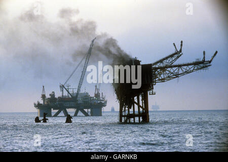 Der Rauch wölbt sich immer noch aus den brennenden Trümmern der Ölförderplattform Piper Alpha, nachdem er explodiert war und 167 Arbeiter an Bord getötet hatte. Es ist die schlimmste Ölbohrinsel-Katastrophe der Welt. Stockfoto