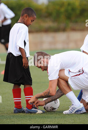 Der Engländer David Beckham knüpft die Schuhspitze eines Jungen während einer Fußballklinik für örtliche Schulkinder im Marvin Lee Stadium, Port of Spain, Trinidad. Stockfoto