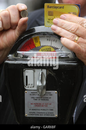 Robert Barnes, Chef von Parkeon, der die Parkplatzmesser in London herstellt, hält ein Stück mit sechs Pence und eine Kreditkarte neben einem originalen 1958 Duncan Single Space Parking Meter am Grosvenor Square in London. Stockfoto
