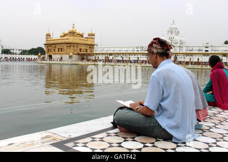 Ein Mann betet vor dem goldenen Tempel in Amritsar, Panjab, Indien Stockfoto