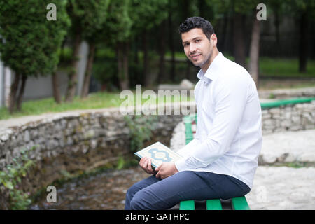 Bescheidenen muslimischer Mann liest das Koran im freien Stockfoto