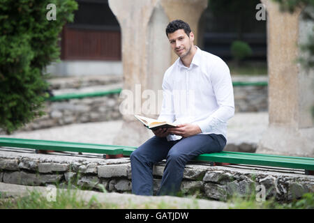Bescheidenen muslimischer Mann liest das Koran im freien Stockfoto
