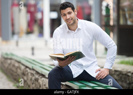 Bescheidenen muslimischer Mann liest das Koran im freien Stockfoto