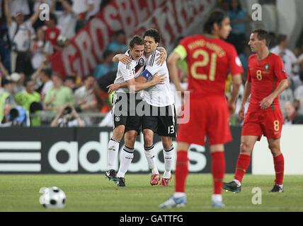 Deutschlands Michael Ballack feiert mit seinem Teamkollegen Miroslav Klose nach dem dritten Tor. Portugals Nuno Gomes und Petit Stand dejected (r) Stockfoto