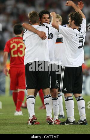 Deutschlands Kapitän Michael Ballack (c) feiert mit seinen Teamkollegen nach dem letzten Pfiff, als Portugals Helder Postiga dejected davonläuft Stockfoto