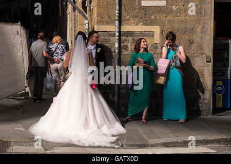 Braut, Bräutigam und Freunden an einer Straßenecke in Florenz, Toskana, Italien. Stockfoto