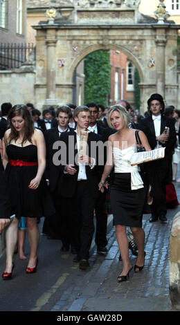 Nachtschwärmer, die ihre Morgenzeitungen in die Hand nehmen, machen sich nach dem Ende der Studienzeit auf den Weg nach Hause, indem sie zum Maiball am Cambridge University Trinity College gehen. Stockfoto