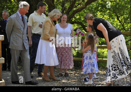 Der Prinz von Wales und die Herzogin von Cornwall werden mit Blumen von den Freunden und der Familie der Besitzer von Solva Woolen Mill, Anna Grime, Mitte, und Tom Grime, zweite links, während ihrer Tour von Solva Woolen Mill, Solva, Wales, überreicht. Stockfoto