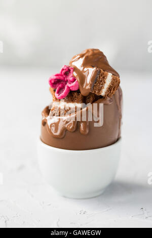 Schokoladen-Ei mit Brownie gefüllt und dekoriert mit einer Zucker-Blume Stockfoto