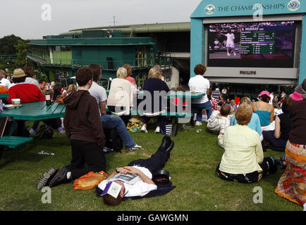 Ein Mitarbeiter macht eine Pause, während Fans Andy Murray während der Wimbledon Championships 2008 im All England Tennis Club in Wimbledon in Aktion von Murray Mount aus beobachten. Stockfoto