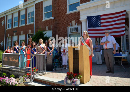 Wantagh, New York, USA. 4. Juli 2016.  KAYLA KNIGHT, Miss Wantagh 2014 singt God Bless America mit Hon. CHRISTOPHER QUINN stehend nach rechts von ihr und Krawatte rot weiß und blau, zum Jahresbeginn die bei der 60. jährliche Miss Wantagh Festzug, eine Tradition der Unabhängigkeitstag auf Long Island. Richter Christopher Quinn ist der Nassau County Überwachung Richter des Amtsgericht und handeln Richter am Obersten Gerichtshof. Bildnachweis: Ann E Parry/Alamy Live-Nachrichten Stockfoto