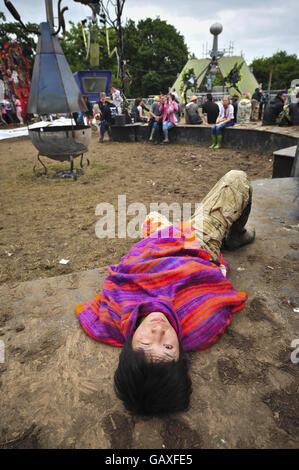 Ein Nachtschwärmer macht ein Nickerchen und schaut aus einem Auge, um zu sehen, was in Trash City am zweiten Tag des Glastonbury Festivals, Somerset, los ist. Stockfoto