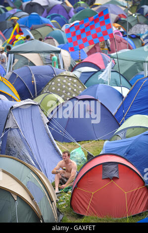 Am zweiten Tag des Glastonbury Festivals, Somerset, sitzt ein nicht identifizierter Festivalbesucher unter Zelten auf dem Campingplatz. Stockfoto