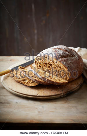 Handwerker, gebackenes Brot auf dunklem Hintergrund mit traditionellen Brot und Brot-Messer auf einem Holztisch Stockfoto