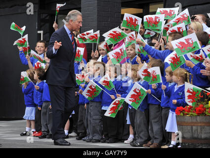 Kinder der Grundschule Penderyn winken walisische Flaggen, während der Prinz von Wales die Waliser Whisky Company Penderyn Distillery besucht. Stockfoto