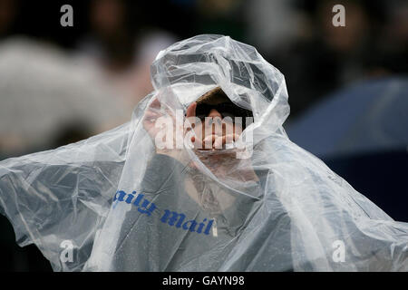 Ein Tennisfan schützt vor dem Regen, da das Spiel während der Wimbledon Championships 2008 im All England Tennis Club in Wimbledon verzögert wird. Stockfoto